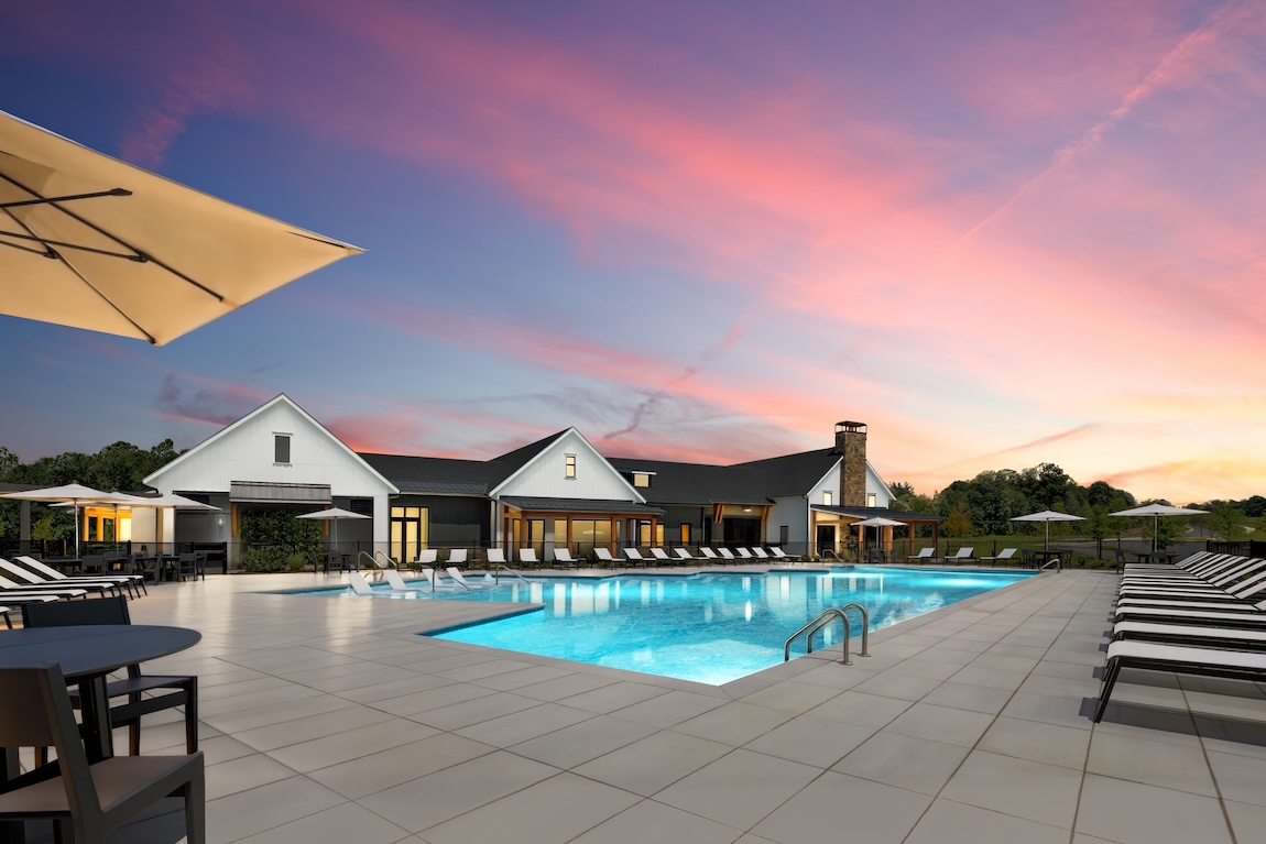 exterior of community clubhouse with pool and sunset backdrop
