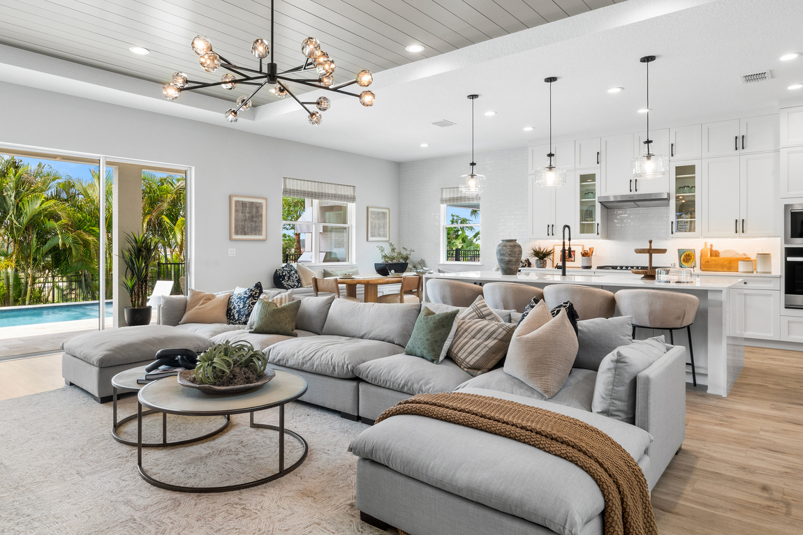 New luxury home with large grey couch, round table and white kitchen design. 