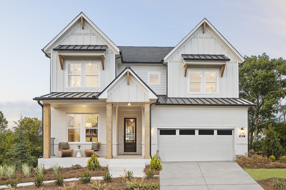 Exterior of luxury home by Toll Brothers with white stone, wooden pillars and board and batton siding in Cumming, Georgia.