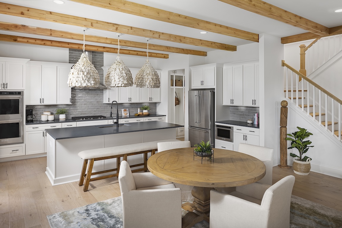 Luxury kitchen design by Toll Brothers featuring wooden beams, quartz countertop, bench island seating and accented light fixutres in Cumming, Georgia.