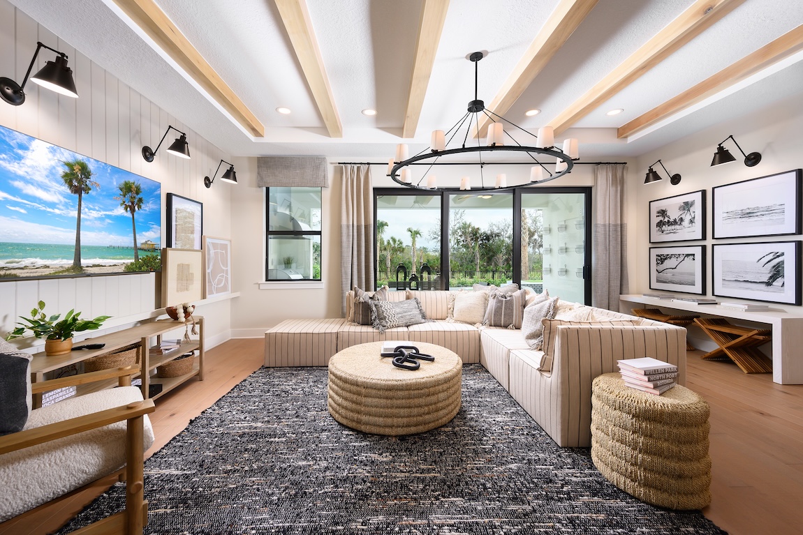Luxury living room with wood beam ceilings, matte black light fixtures and L-shaped couch in Vero Beach, Florida.