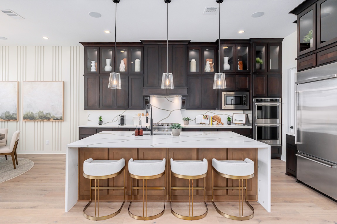 Modern kitchen with waterfall island, dark wood cabinetry, and pendant lighting above bar seating.