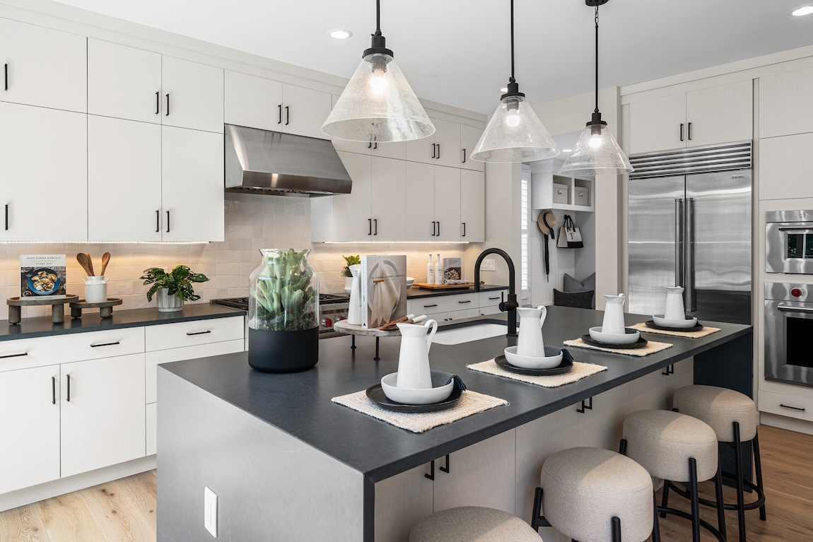 modern kitchen with white cabinetry and glass overhead lighting