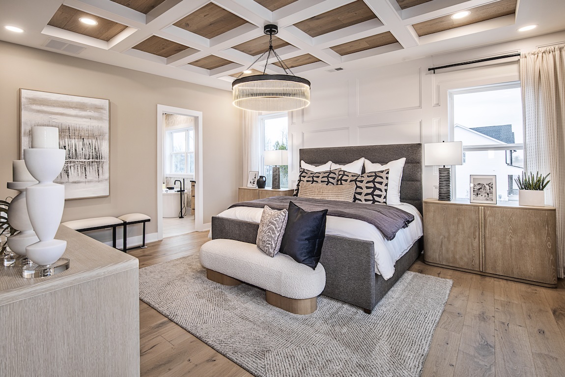 Modern primary bedroom with coffered ceiling, layered textures, and soft natural light for a serene retreat.