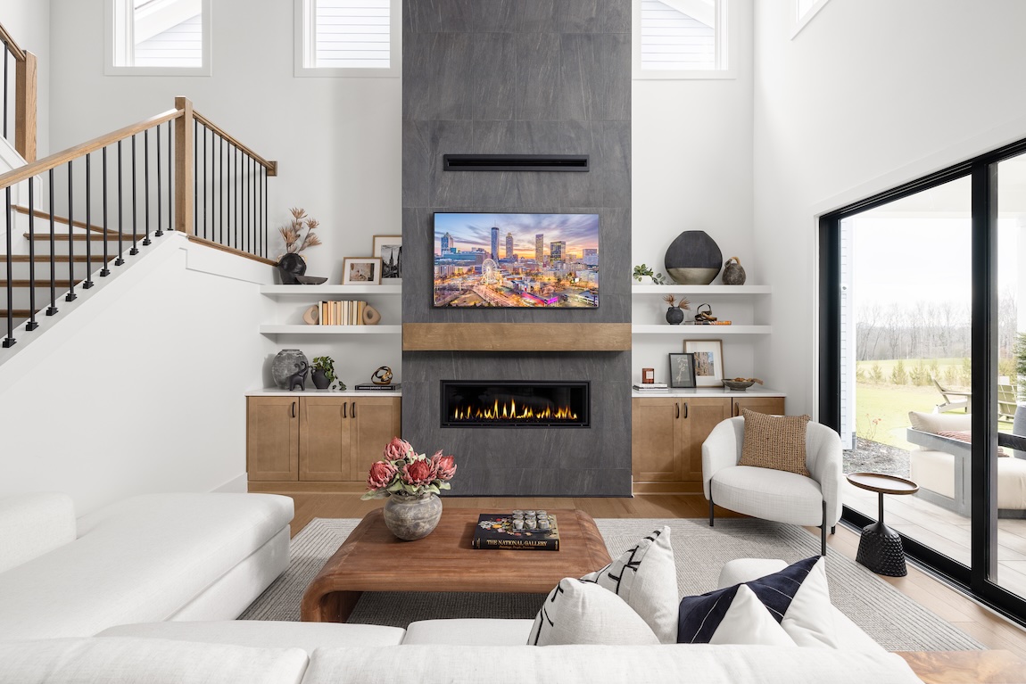modern great room with a stone fireplace and glass sliding doors.